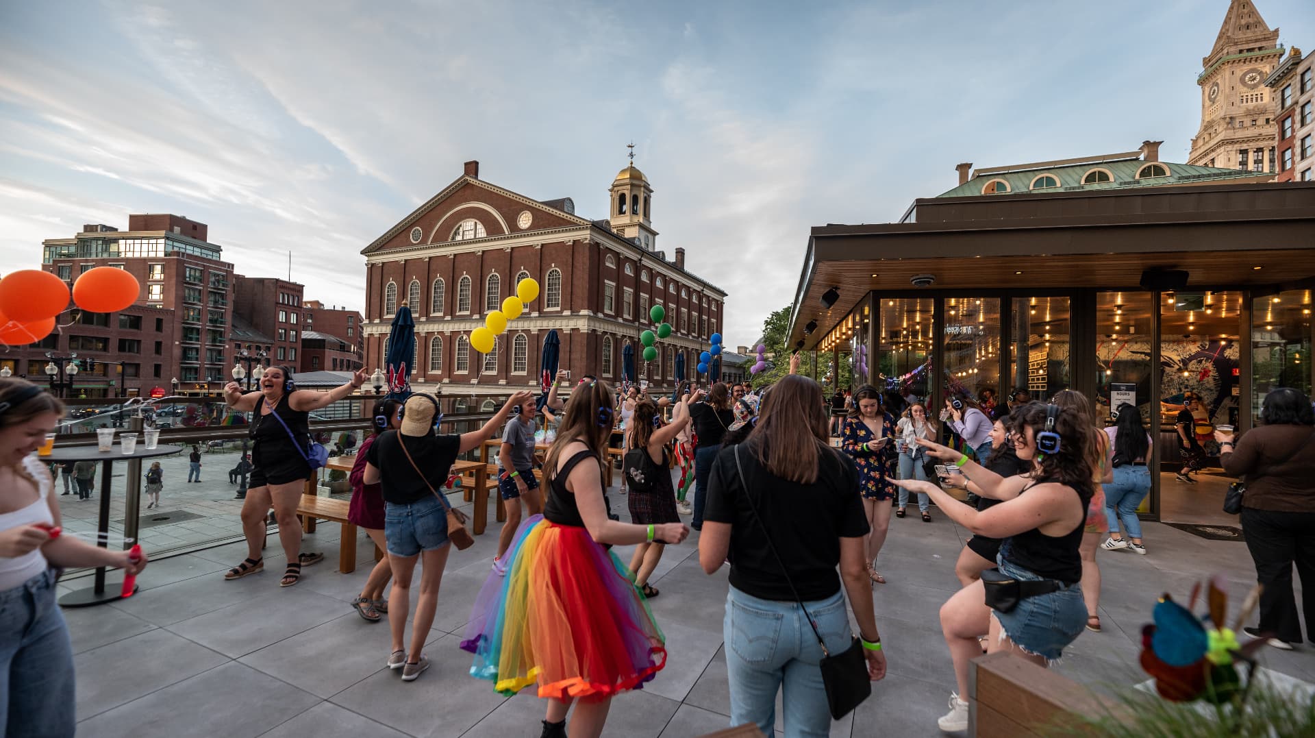 Silent disco party dancing outside Faneuil Hall in Boston at sunset