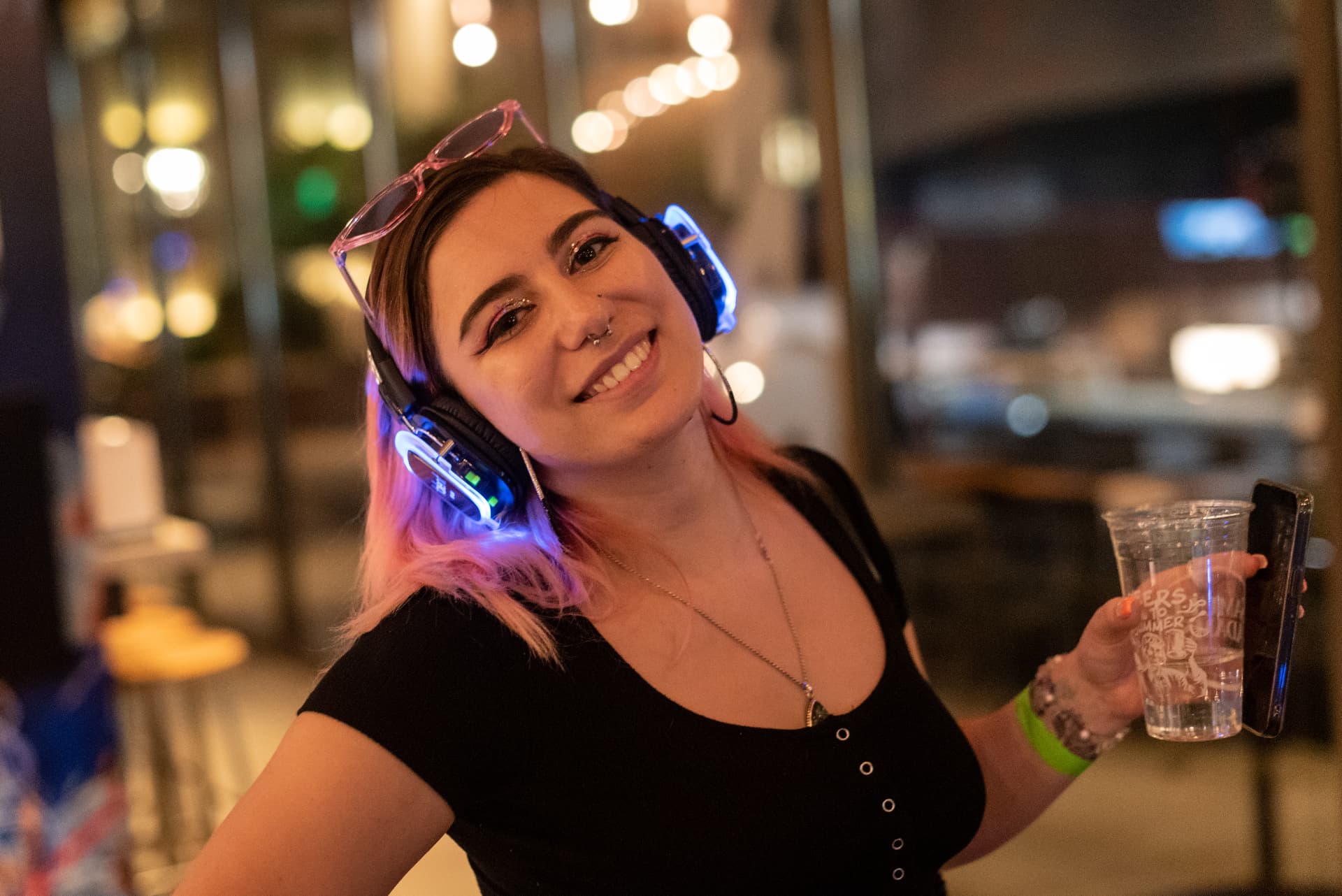 Smiling guest wearing LED-lit silent disco headphones at a night event