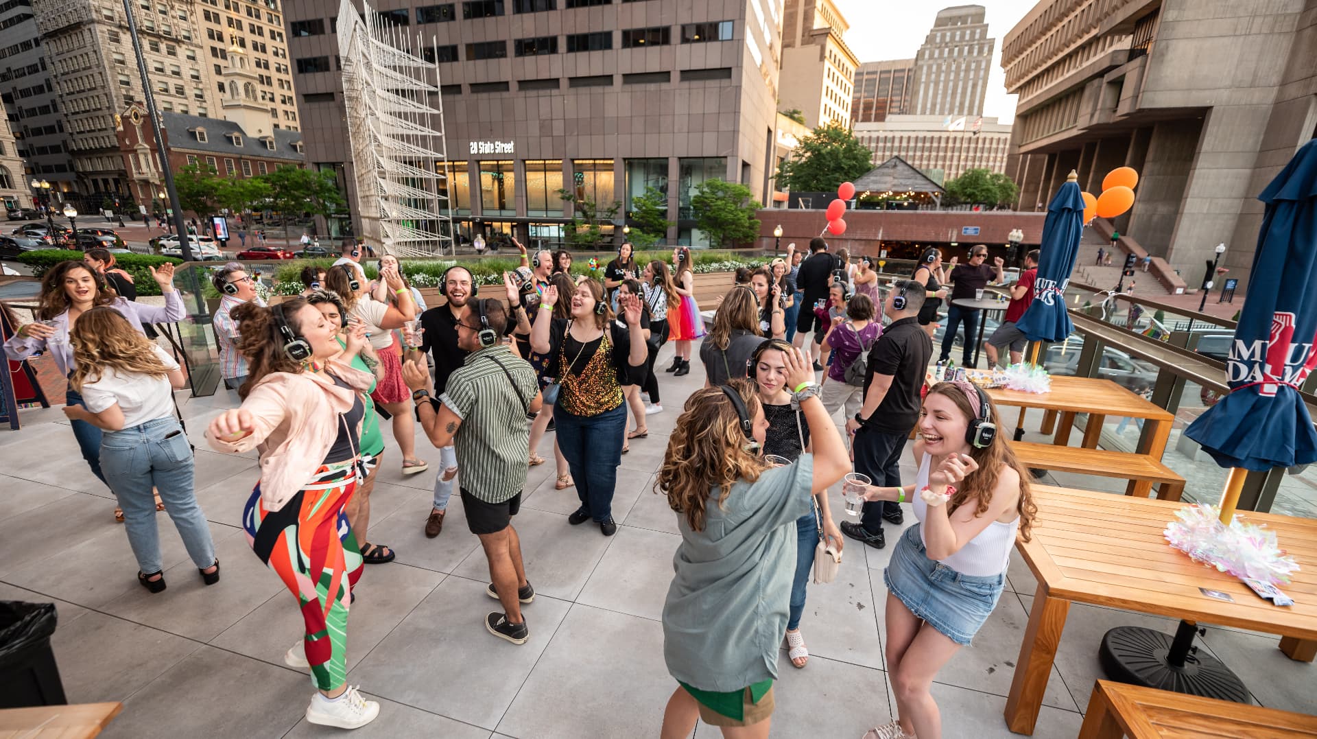 Crowd dancing in silent disco headphones at an outdoor Boston plaza event