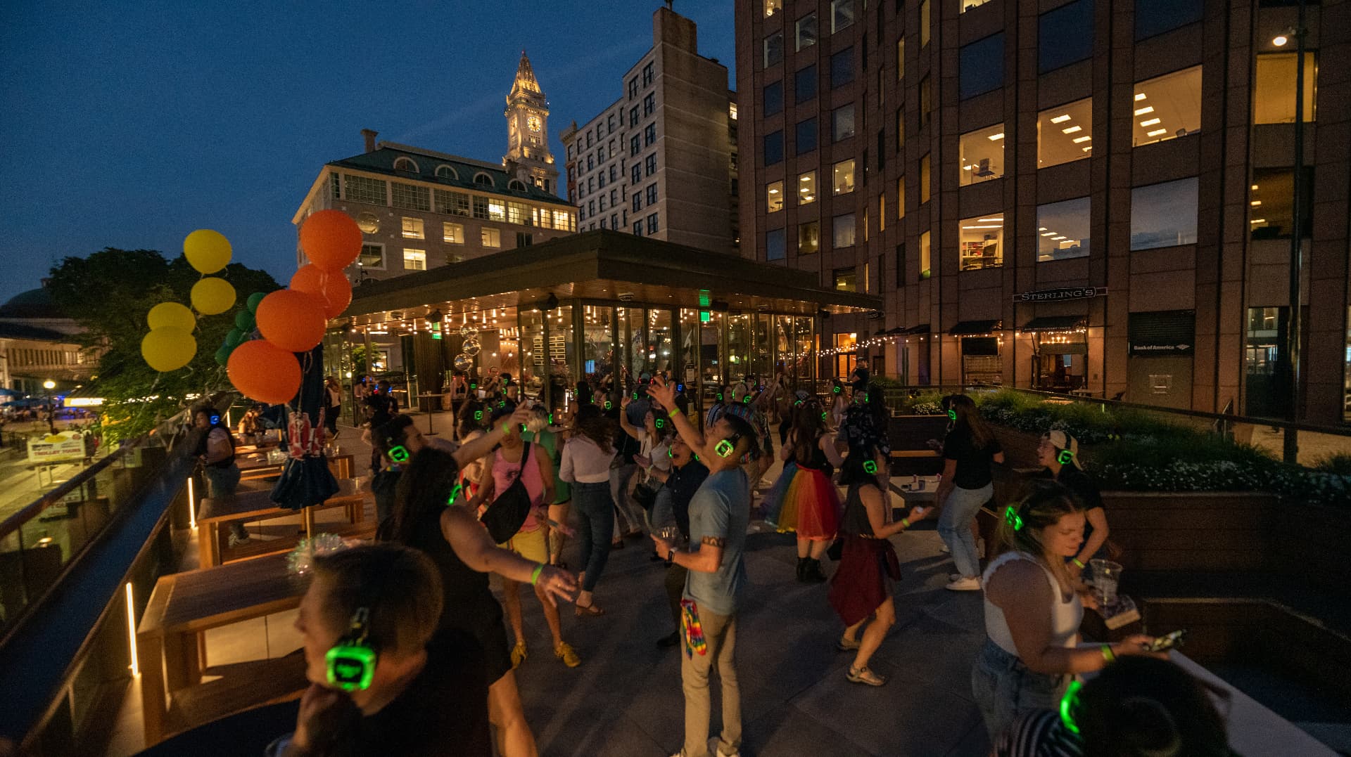 Nighttime silent disco with glowing green headphones and string lights